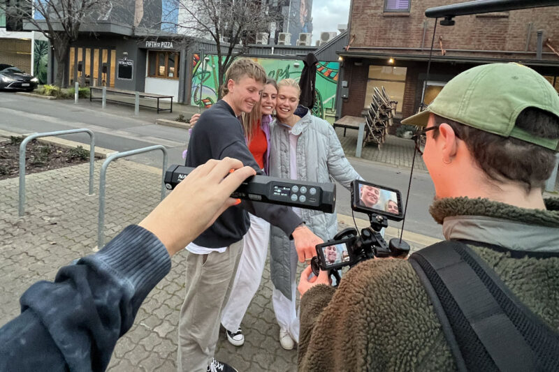 Three people smiling for the camera whilst being filmed on a street